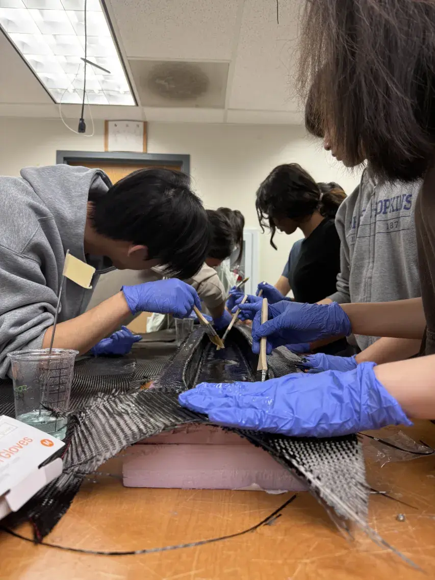Team applying carbon fiber layup over the foam core